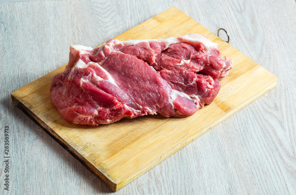 Raw meat on wooden board on table Raw meat on wooden board on table