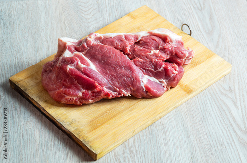Raw meat on wooden board on table