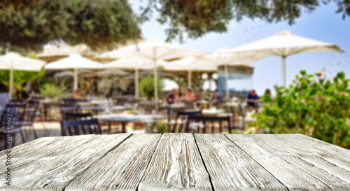 Table background. Sunny summer day. Blurred umbrellas and chairs in distance.
