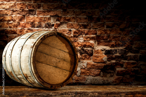 Tablou Canvas A barrel on wooden table and brick wall background.