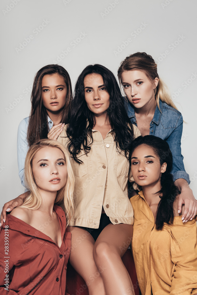 Obraz premium front view of five attractive multiethnic feminists in colorful shirts looking at camera isolated on grey