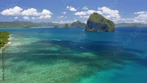 Aerial drone view of Pinagbuyutan island with cloud shades moving on ocean surface. Trip banca boats in the sea. El Nido, Palawan, Philippines photo