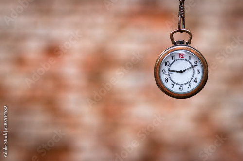 Pocket watch against blurred brick wall. Time concept