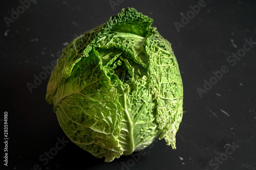 Closeup of savoy cole cabbage on black desk with marble effect.