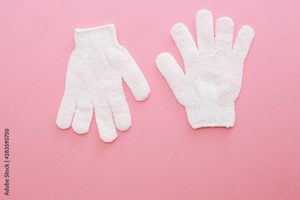 Woman exfoliating massage glove for shower on pink background.Gloves for use in the shower for massage and scrub. Beauty background with cosmetic products. Beauty, health and spa concept Woman exfoliating massage glove for shower on pink background.Gloves for use in the shower for massage and scrub. Beauty background with cosmetic products. Beauty, health and spa concept