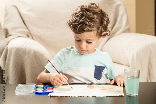 Child painting with watercolors on paper.