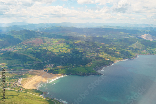 Aerial view from the aircraft window of Bilbao surrounding area. Photography of mountain range, Bay of Biscay, beach in Basque country in summer day. Suitable for greeting card, postcard, poster