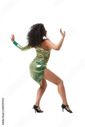 Beautiful girl with magnificent curls in a green shiny stage dress dancing rear view isolated on a white background.