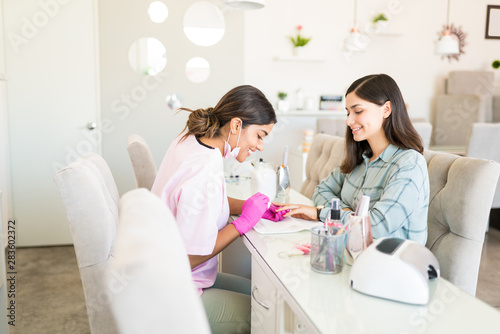 Closeup Of Beautician Applying Nail At Salon