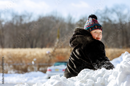 Happy child playing in snow on cold winter day.
