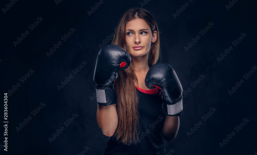 Cheerful smiling woman with long hair is posing for photographer over dark background.