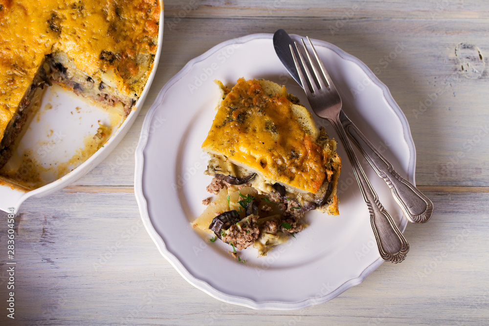 Traditional moussaka on plate and in baking dish