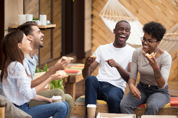 Happy diverse young people eating pizza having fun