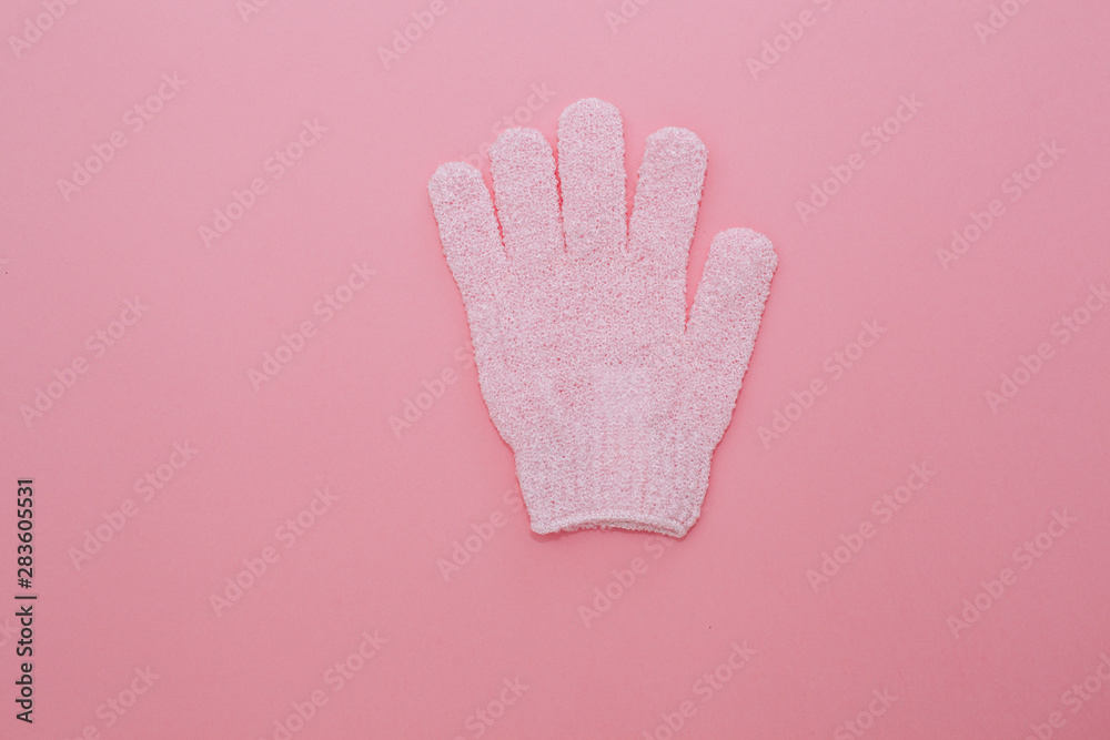 Obraz premium Woman exfoliating massage glove for shower on pink background.Gloves for use in the shower for massage and scrub. Beauty background with cosmetic products. Beauty, health and spa concept