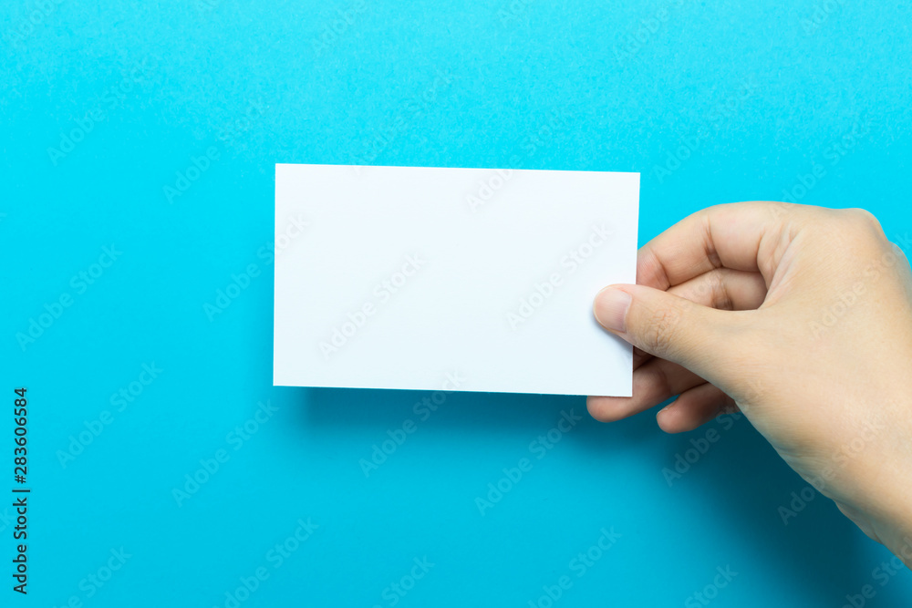 Fototapeta premium Hand holding up a note card on a blue background