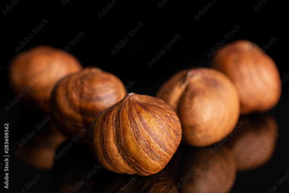 Group of five whole ripe brown hazelnut arranged symmetrically in closeup isolated on black glass Group of five whole ripe brown hazelnut arranged symmetrically in closeup isolated on black glass