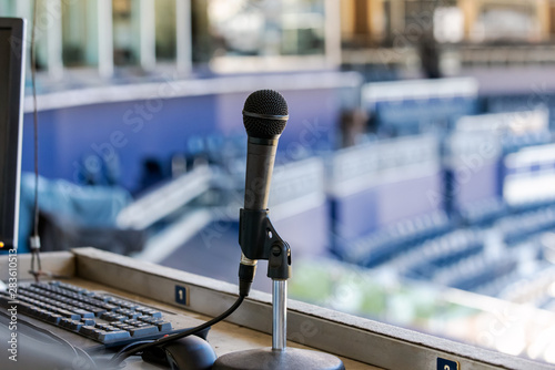 Microphone resting in holder on desk of announcers booth for baseball stadium.