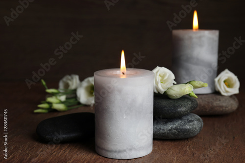 Burning candles, spa stones and flowers on wooden table