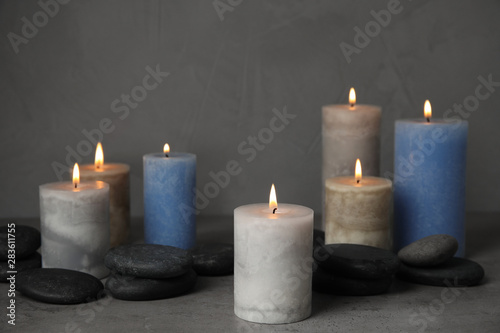 Burning candles and spa stones on grey table