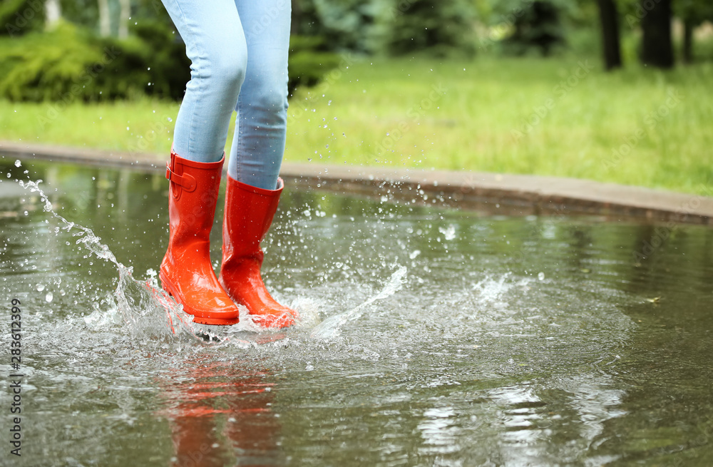 Woman with red rubber boots jumping in puddle, closeup. Rainy weather  Photos | Adobe Stock
