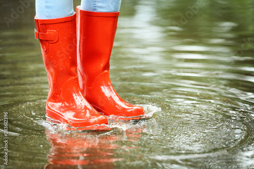 Foto Woman with red rubber boots in puddle, closeup. Rainy weather