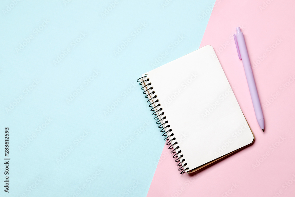Notebook with pen on a blue and pink background. Place for text Notebook with pen on a blue and pink background. Place for text