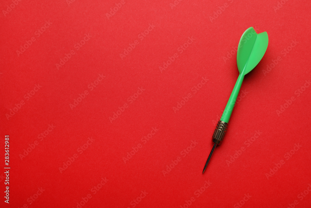 Green dart arrow on red background, top view with space for text Green dart arrow on red background, top view with space for text