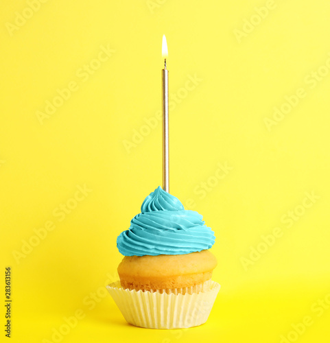 Birthday cupcake with candle on yellow background