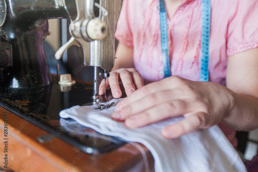 woman seamstress using retro sewing machine woman seamstress using retro sewing machine