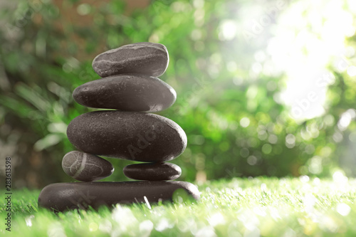 Stack of stones on green grass against blurred background  space for text. Zen concept