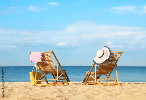 Empty wooden sunbeds and beach accessories on sandy shore