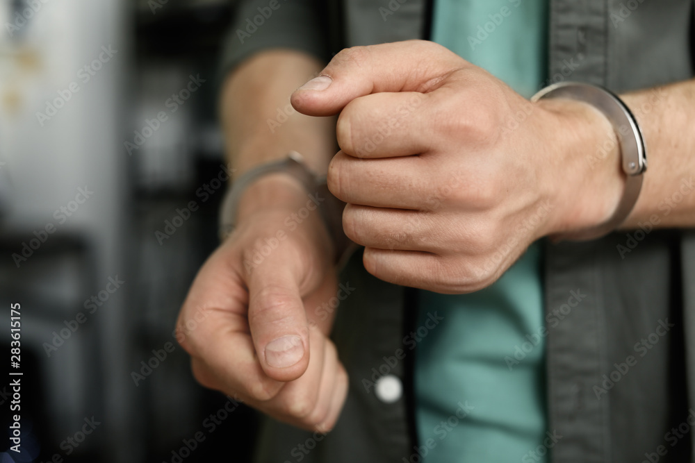 Man detained in handcuffs indoors, closeup view. Criminal law