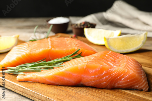 Wooden board with salmon fillet on table, closeup