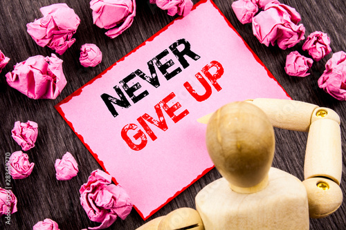 Conceptual hand text showing Never Give Up. Concept meaning Motivation Quote For Success Achievement Challenge written Sticky Note Holding By Sculpture the wooden background. photo