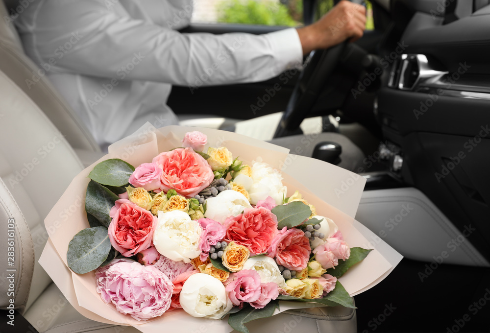 Young man with beautiful flower bouquet in car, closeup view Young man with beautiful flower bouquet in car, closeup view