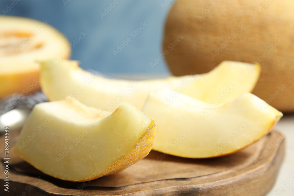 Wooden board with slices of ripe melon on table, closeup