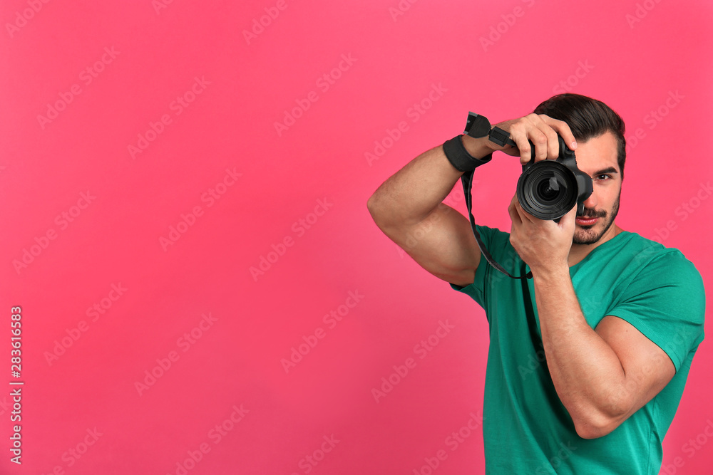 Young professional photographer taking picture on pink background. Space for text Young professional photographer taking picture on pink background. Space for text