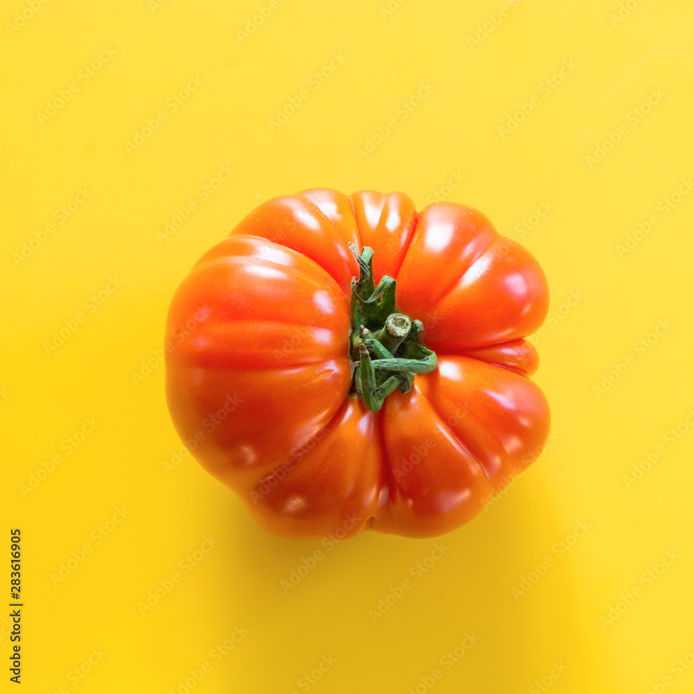 Ugly ripe tomato on yellow. Concept organic vegetables.