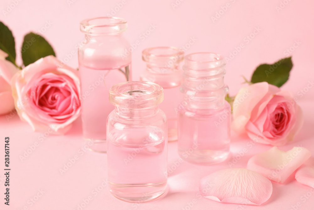 Bottles of essential oil and roses on pink background Bottles of essential oil and roses on pink background
