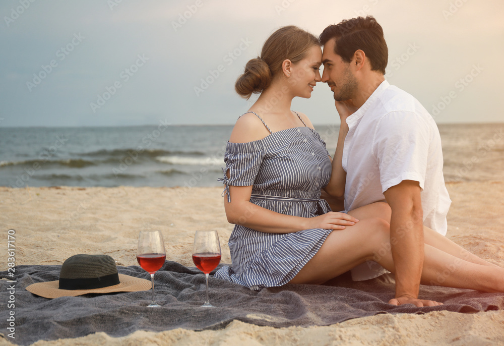 Happy young couple having picnic at sea beach