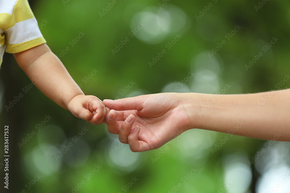 Mother with her baby holding hands together in park on summer day Mother with her baby holding hands together in park on summer day