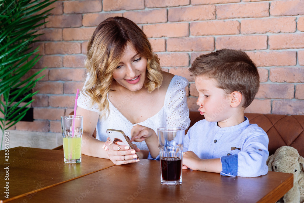 Mom and her son looking at her phone. She is showing him some pictures. Mom and her son looking at her phone. She is showing him some pictures.