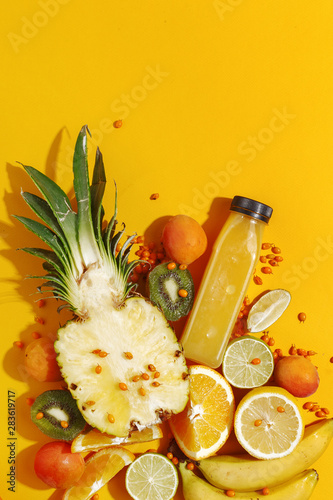 Fototapeta Naklejka Na Ścianę i Meble -  Bottle with fruit smoothie, various ripe juicy fruits and sliced pineapple on a yellow background. Detox. Healthy eating concept. Top view
