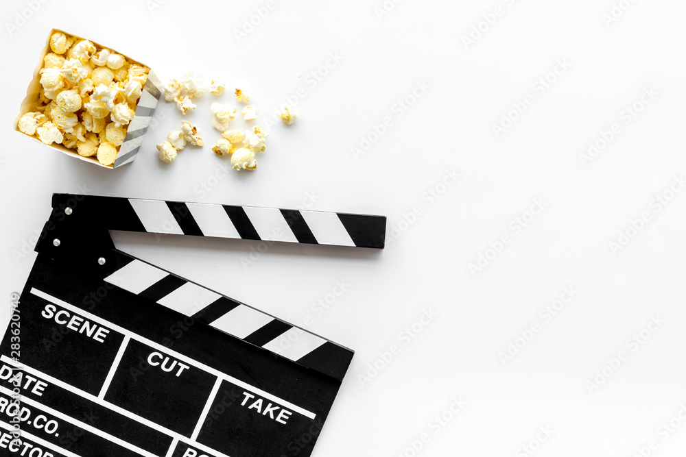 Movie premiere concept with clapperboard, popcorn on white background top view space for text