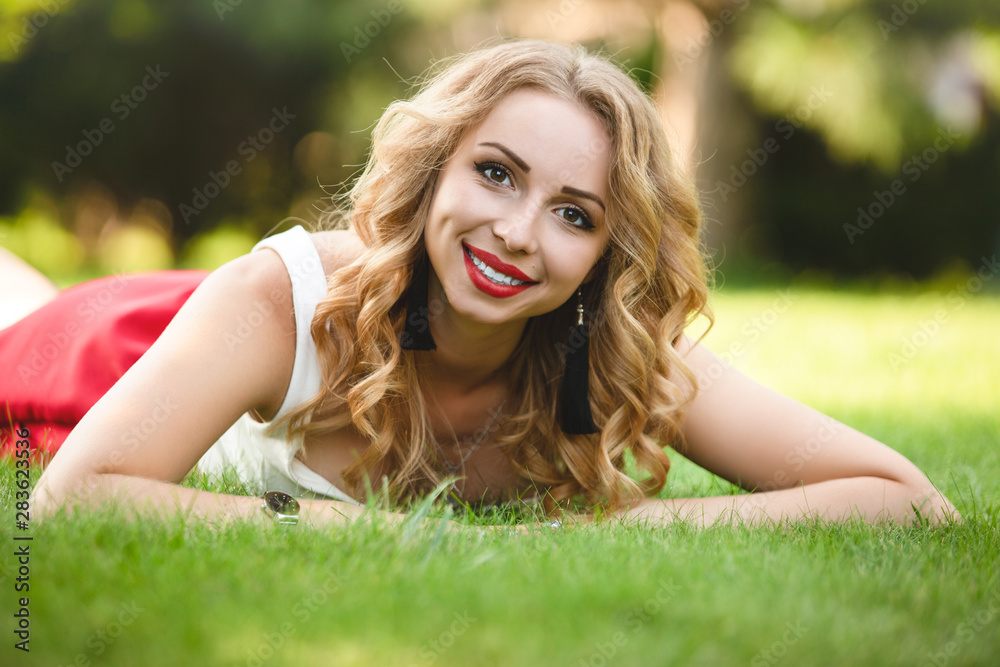 Top view of attractive female model lying on green grass in park and looking at camera during time for taking rest, portrait of Caucasian woman with blond hair spending day at nature Top view of attractive female model lying on green grass in park and looking at camera during time for taking rest, portrait of Caucasian woman with blond hair spending day at nature