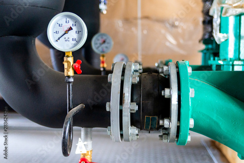 Fotografija System of hot water pipes with manometer in boiler room.