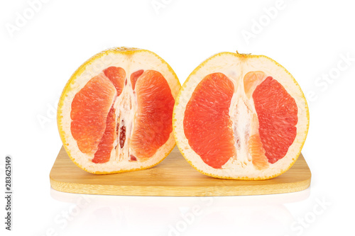 Group of two halves of fresh pink grapefruit on bamboo cutting board isolated on white background