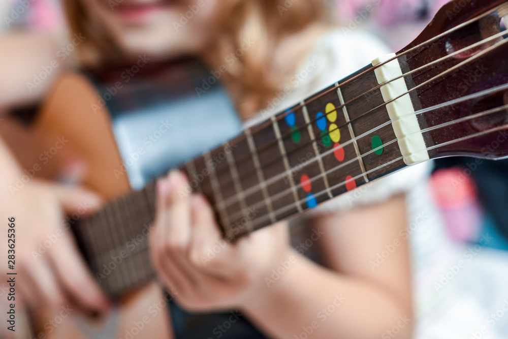 Fototapeta premium Girl learns to play guitar during a music lesson on the instrument