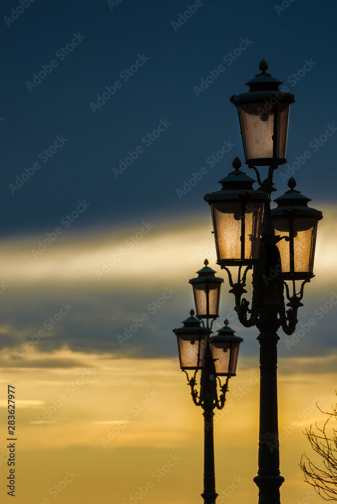 Old traditional Venice street lamps at sunset in a romantic and unique atmosphere (with copy space)