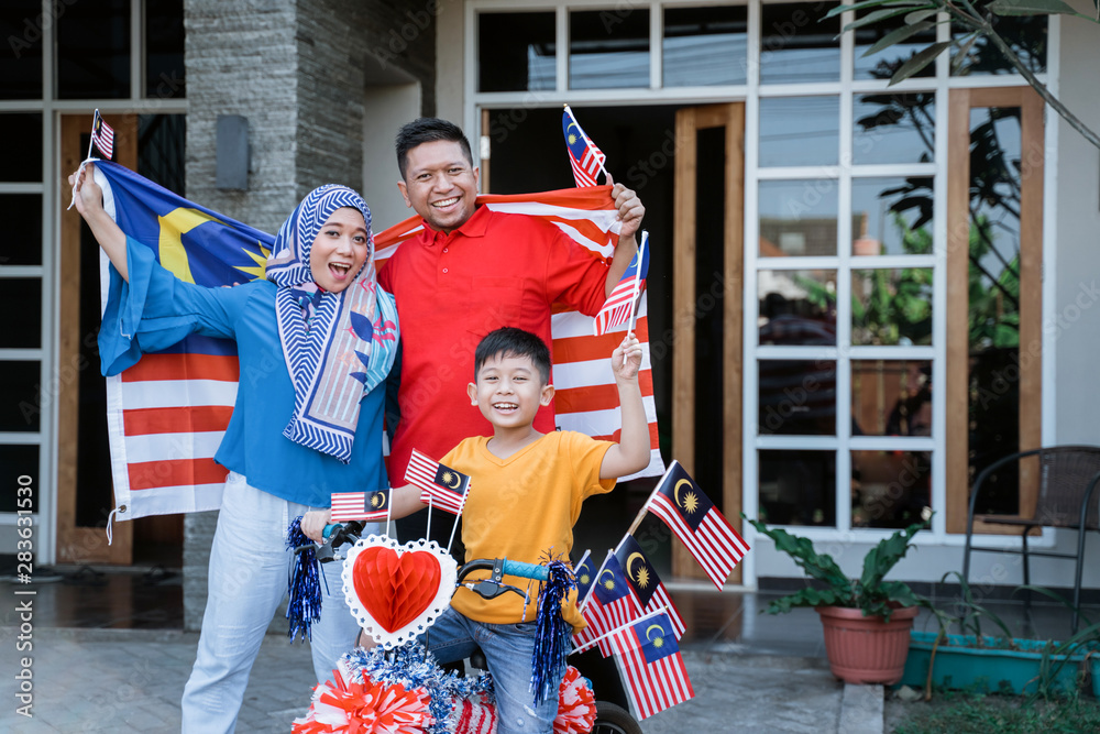 proud family with malaysia flag and decorated bicyle on independence day